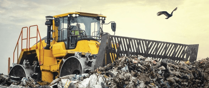 Yellow bulldozer pushing a large pile of dirt or debris.