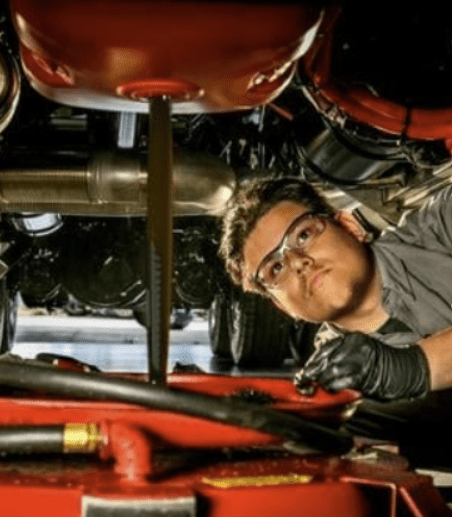 Mechanic inspecting car engine from underneath.
