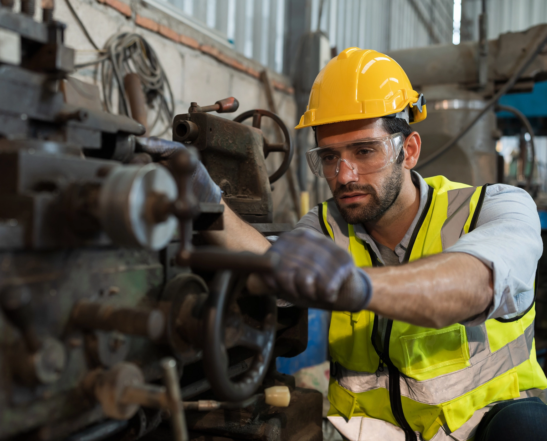 Worker operating machinery in safety gear.