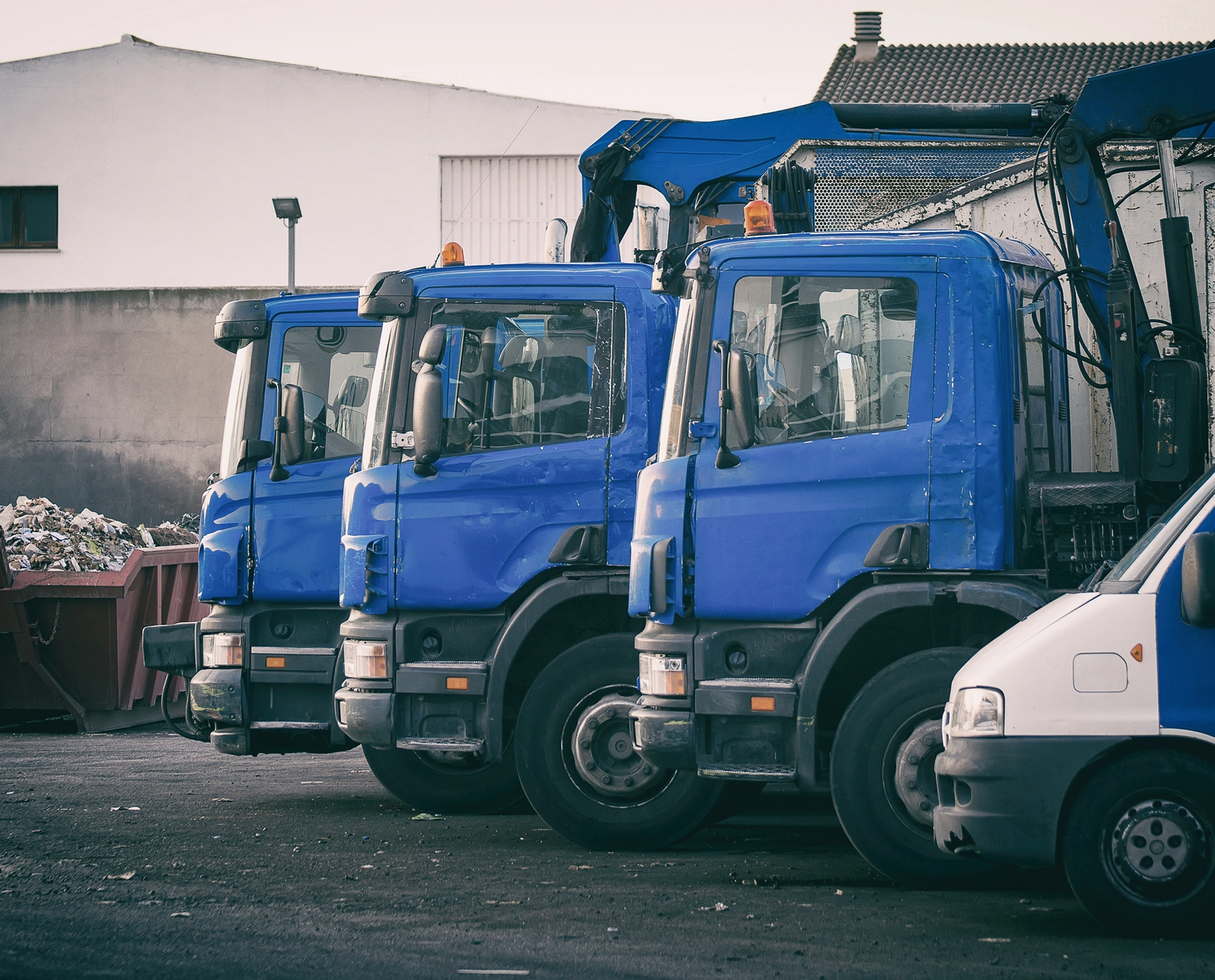 Blue trucks parked in industrial area.